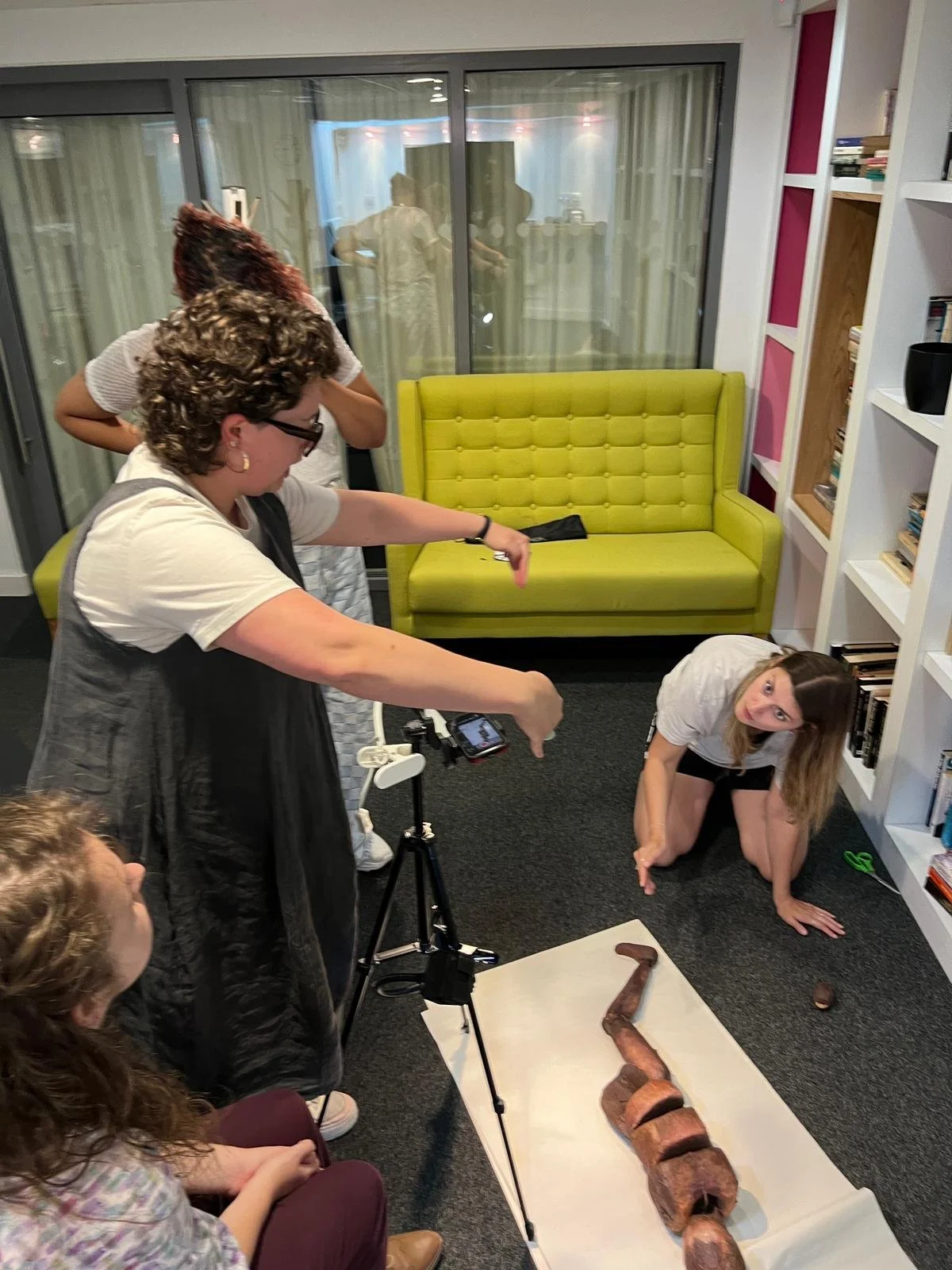 A group of people capturing photos of a wooden puppet, showcasing their enthusiasm and engagement with the subject.