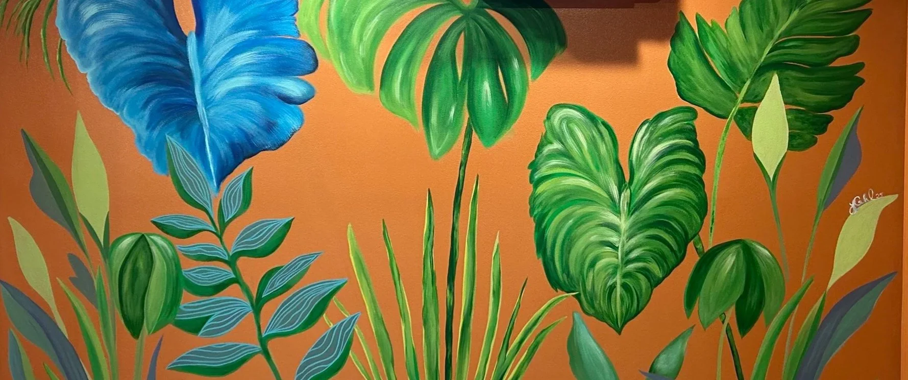 Colorful mural of various green and blue tropical leaves against an orange background.