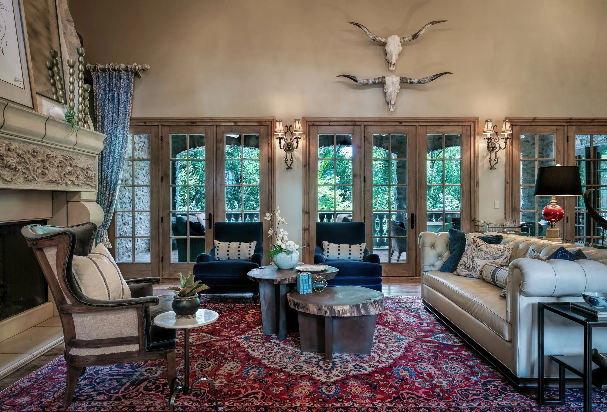Formal living room with carved stone fireplace, longhorn skulls, and layered antique rug, Overland Park, Kansas.