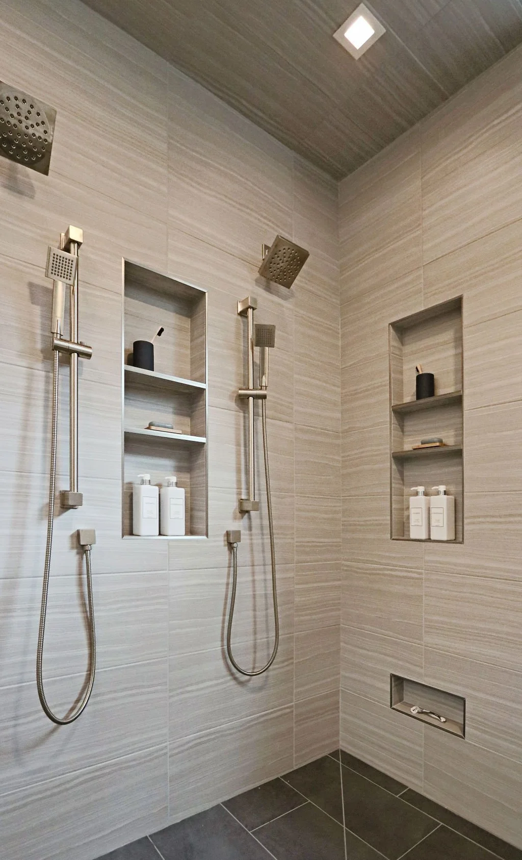 Two-person shower with dual rainfall showerheads, tiled niches, and handheld sprayers