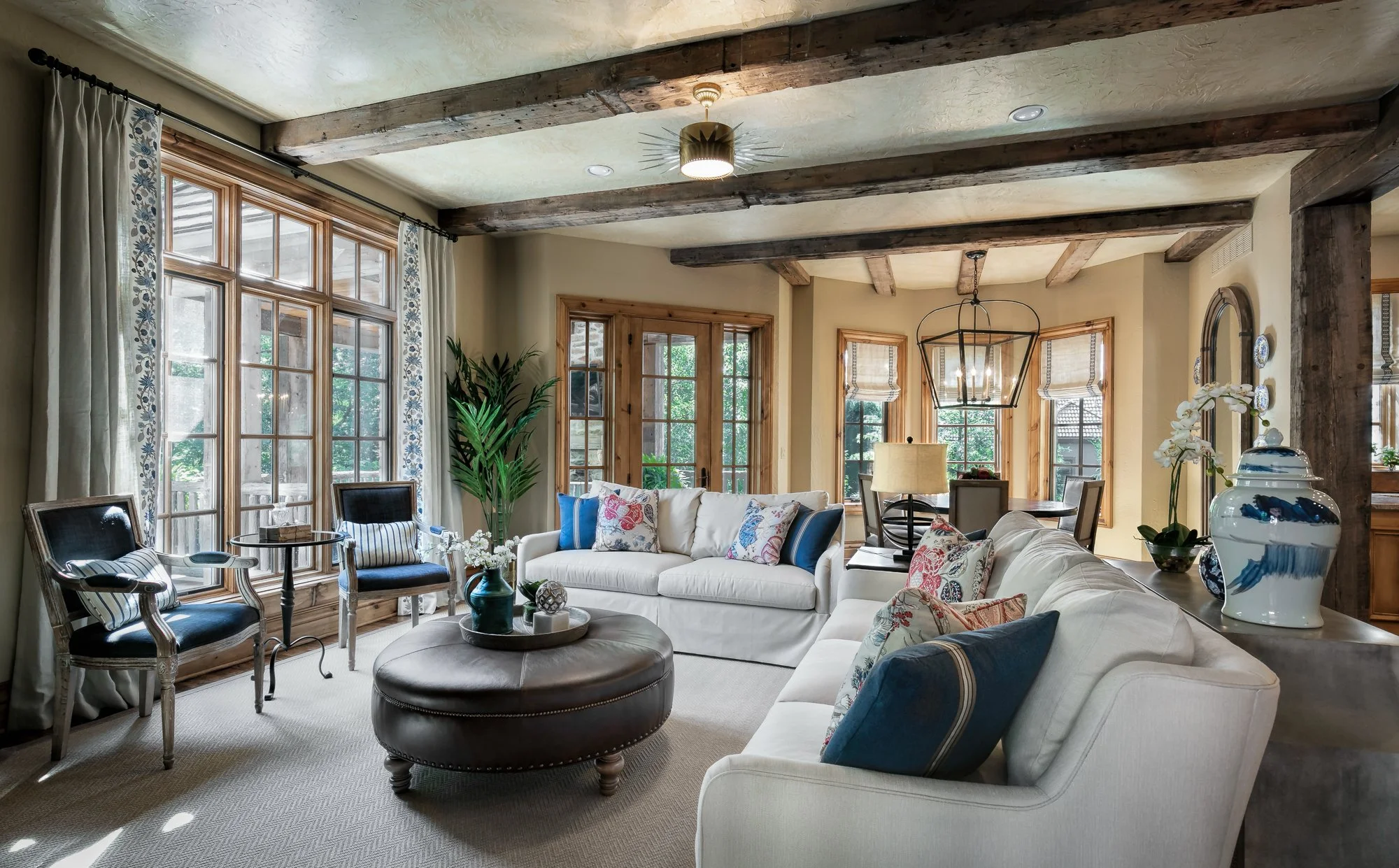 French Country hearth room with blue and off-white palette, beamed ceiling, and dining area beyond, Overland Park, Kansas.