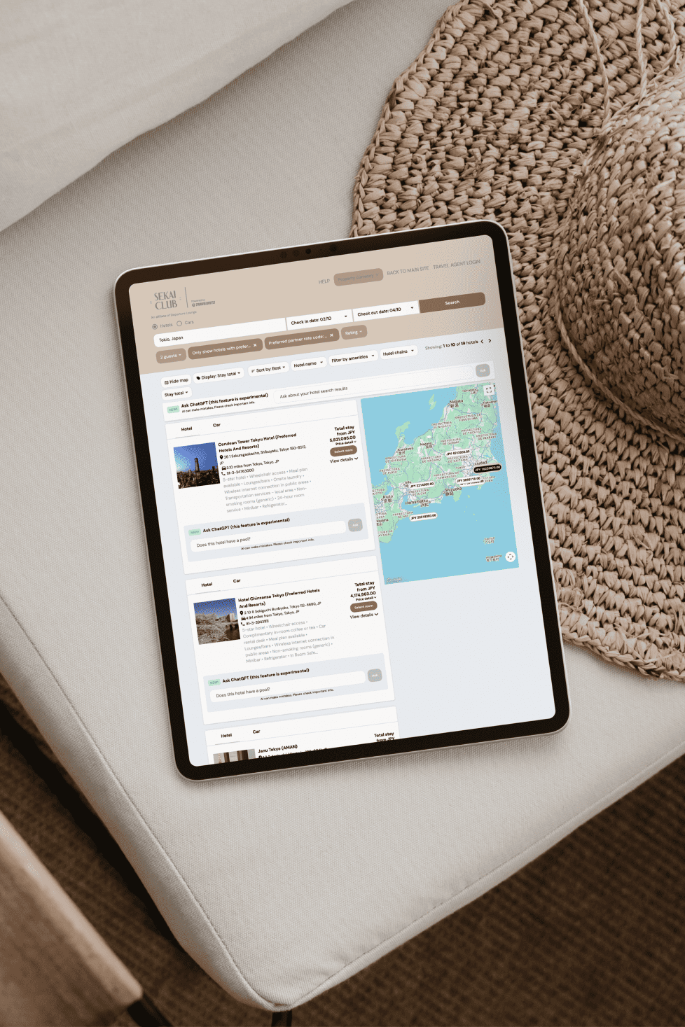 Tablet displaying a travel booking website with hotel options and a map, resting on a white cushioned surface with a woven basket nearby.