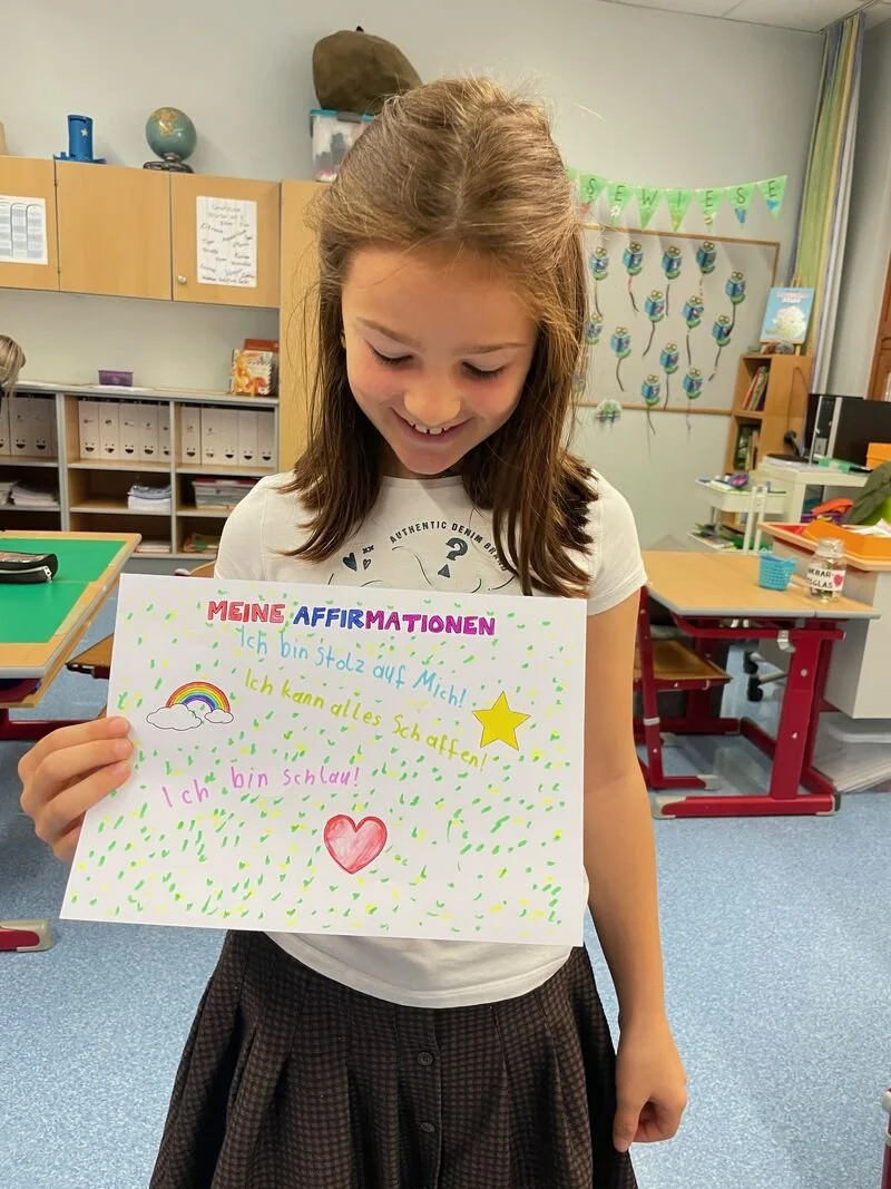 Kind hält eine Zeichnung zum Thema Dankbarkeit im Rahmen eines Achtsamkeitstages in der Volksschule.