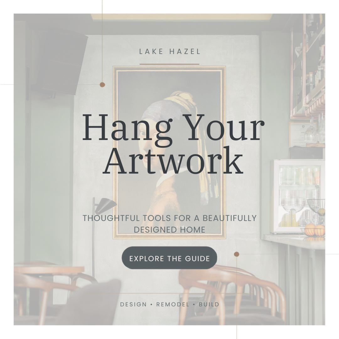 A promotional overlay for a home decor guide, featuring a framed painting of a woman with her back turned, hanging in a modern kitchen or living space. Text on the overlay says 'Hang Your Artwork' and 'Thoughtful tools for a beautifully designed home