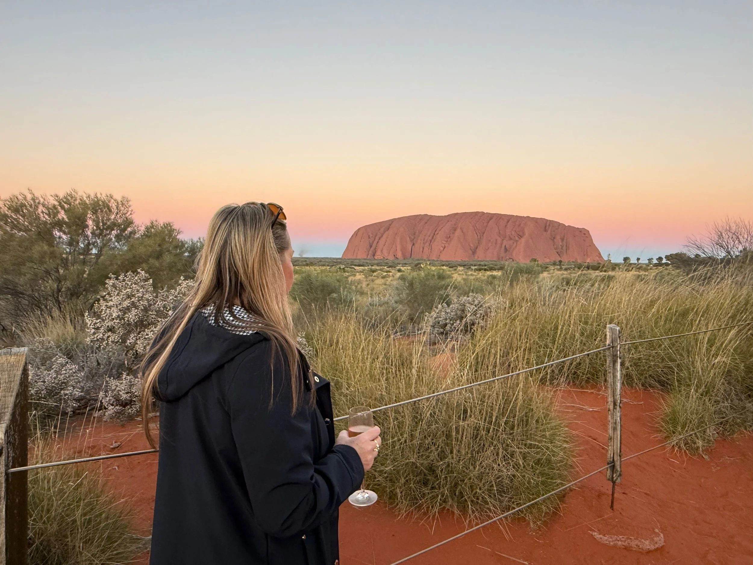 Women looking at Uluru sunset while drinking wine.