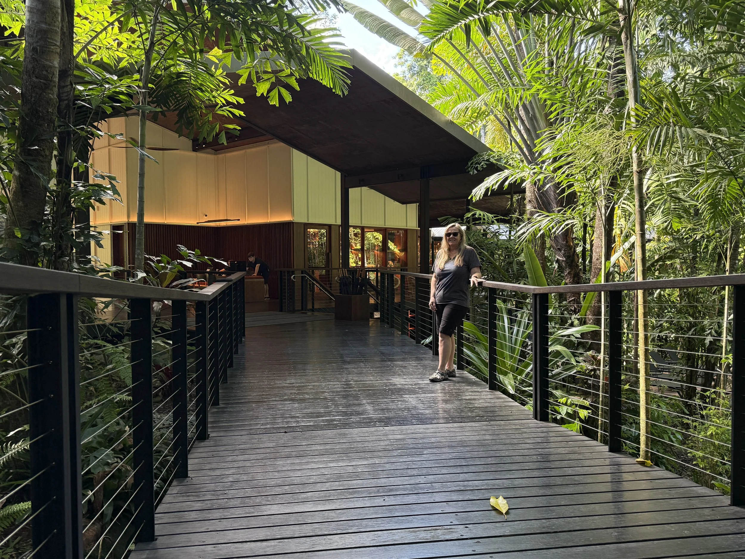 Luxurious treehouse restaurant with elegant dining setup surrounded by lush greenery, featuring polished wooden floors, ambient lighting, and a central table arrangement.