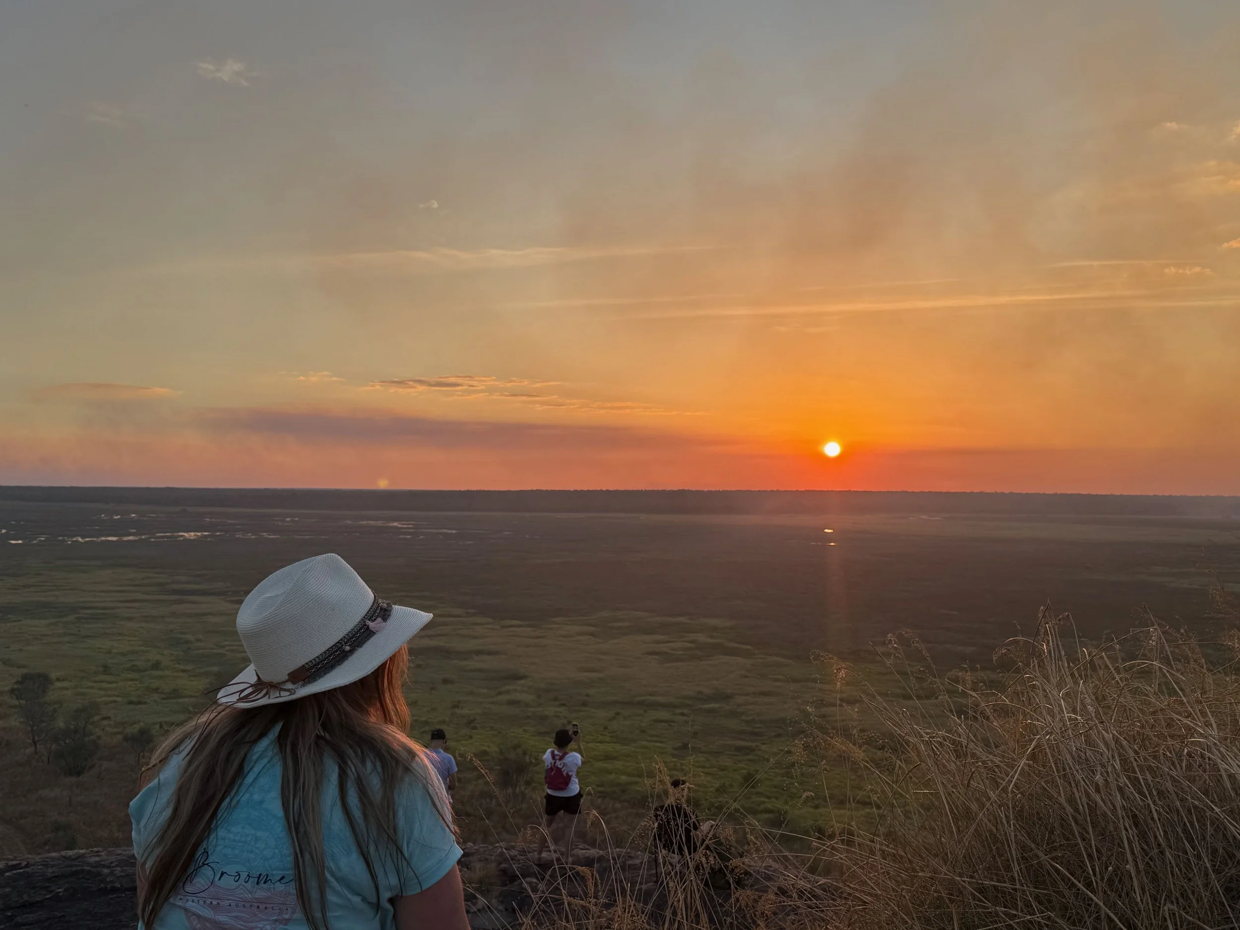 A lady in. a white hat watching sunset at Ubirr in Kakadu National Park