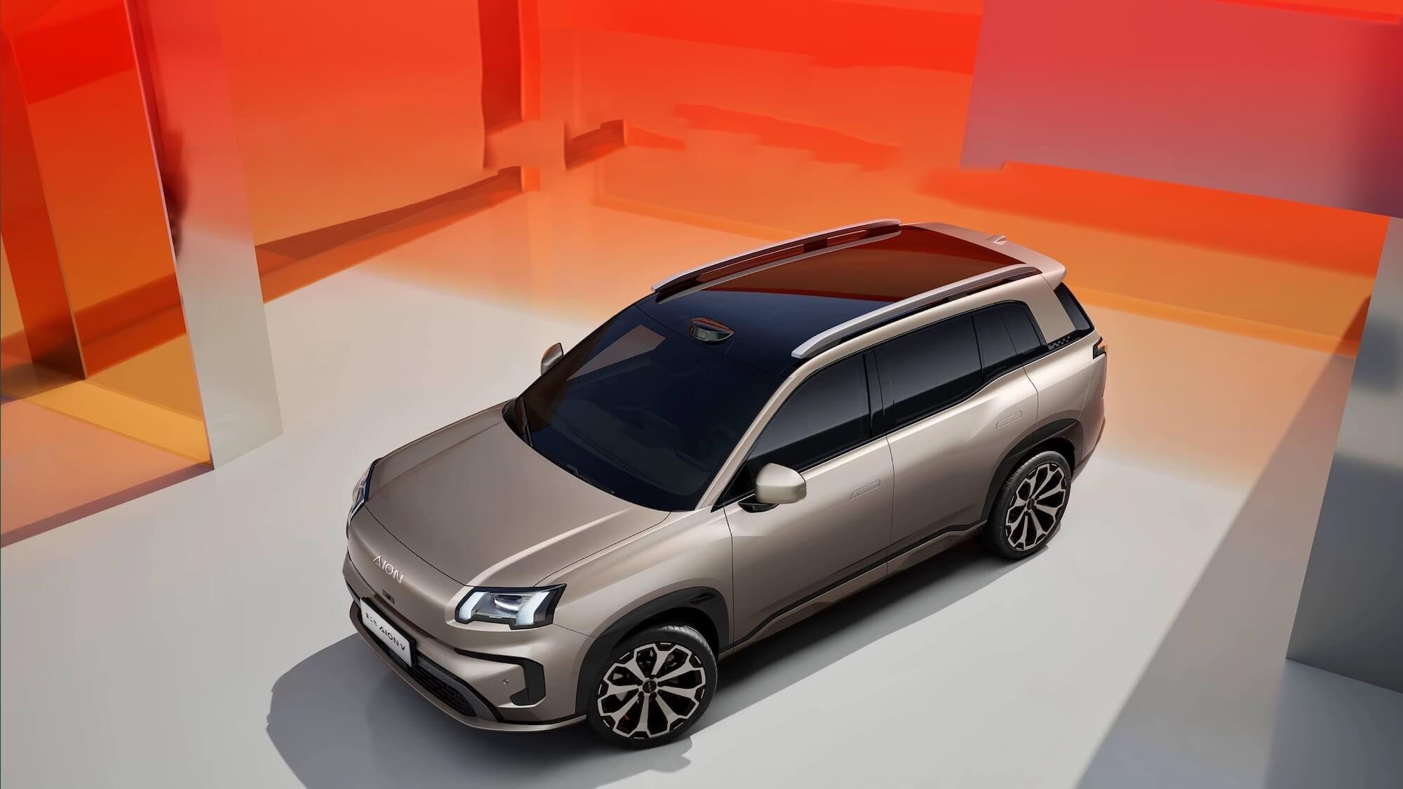 Coche deportivo de color gris en un espacio moderno con paredes naranjas y blancas.