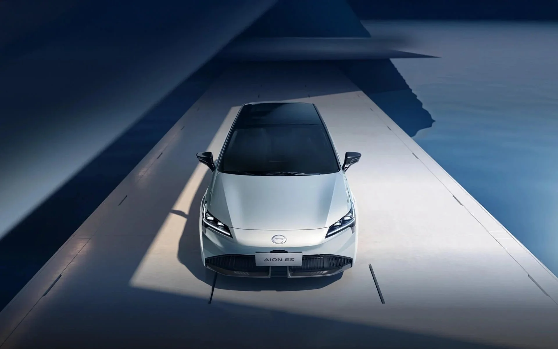 Coche eléctrico plateado, modelo Aion ES, en exhibición en un entorno moderno