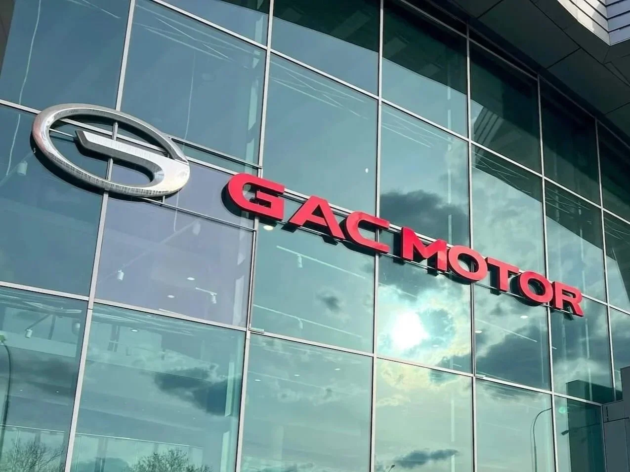 Vista de un edificio de vidrio con el logo de GAC y el letrero en rojo que dice GAC MOTOR.