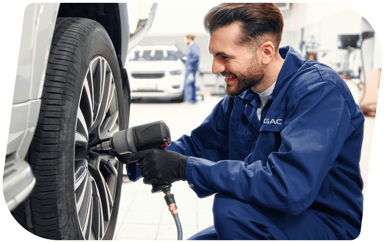 Un técnico automotriz reparando una llanta de un coche en un taller.