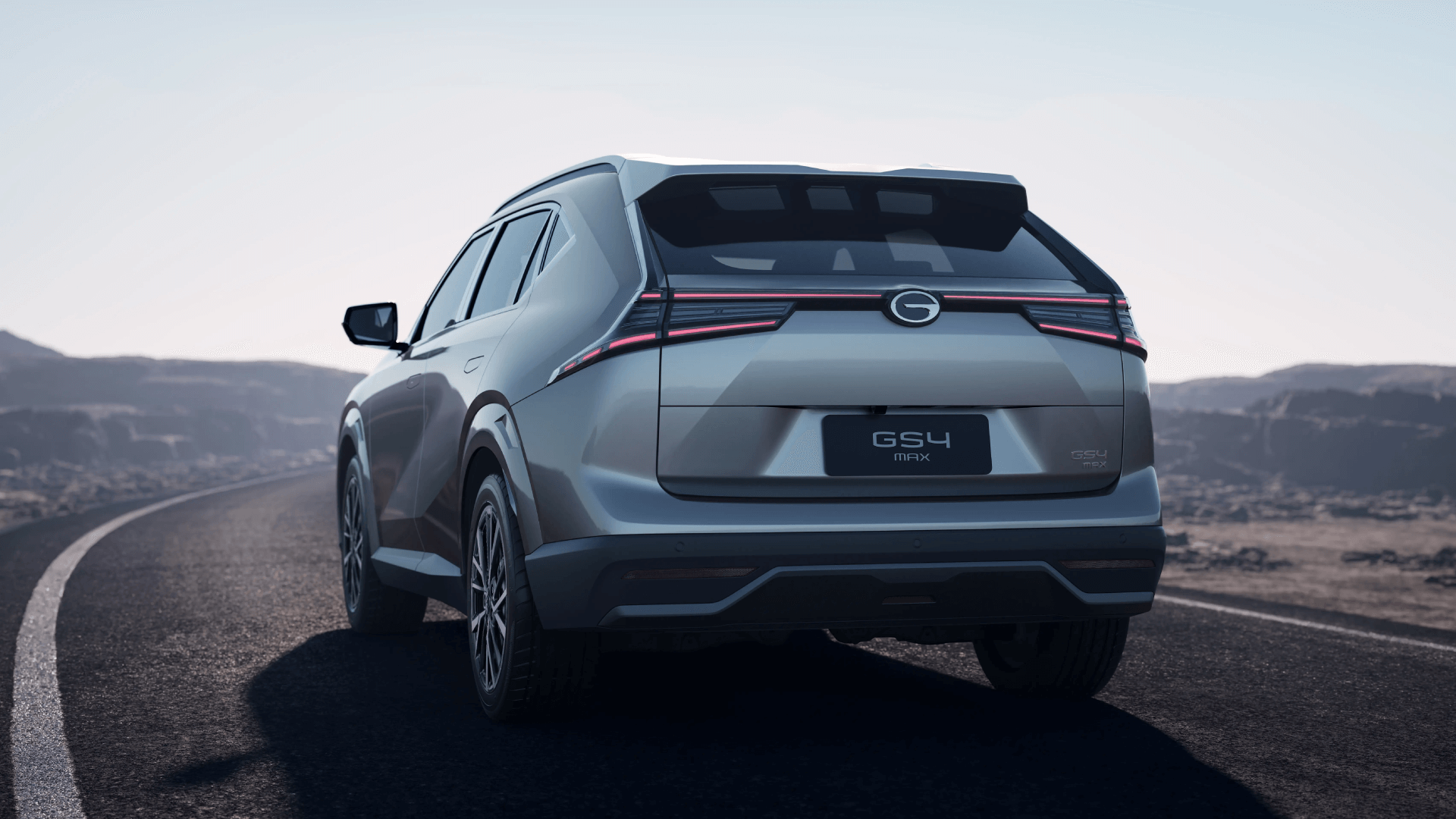 Automóvil marca GAC de color gris en una carretera en un paisaje montañoso.