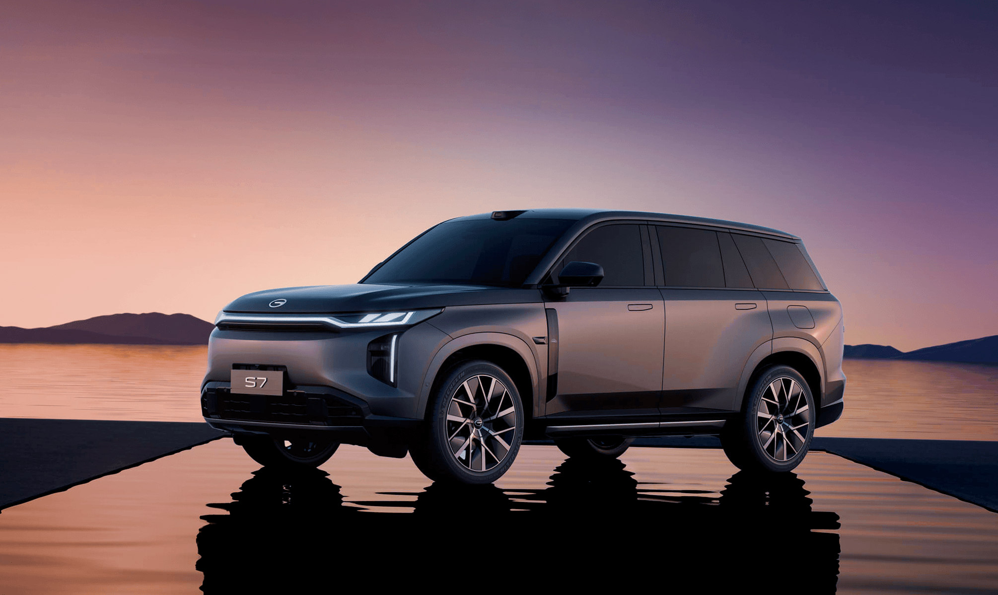 GAC S7 PHEV gris sobre plataforma junto al agua, SUV híbrido enchufable de lujo.