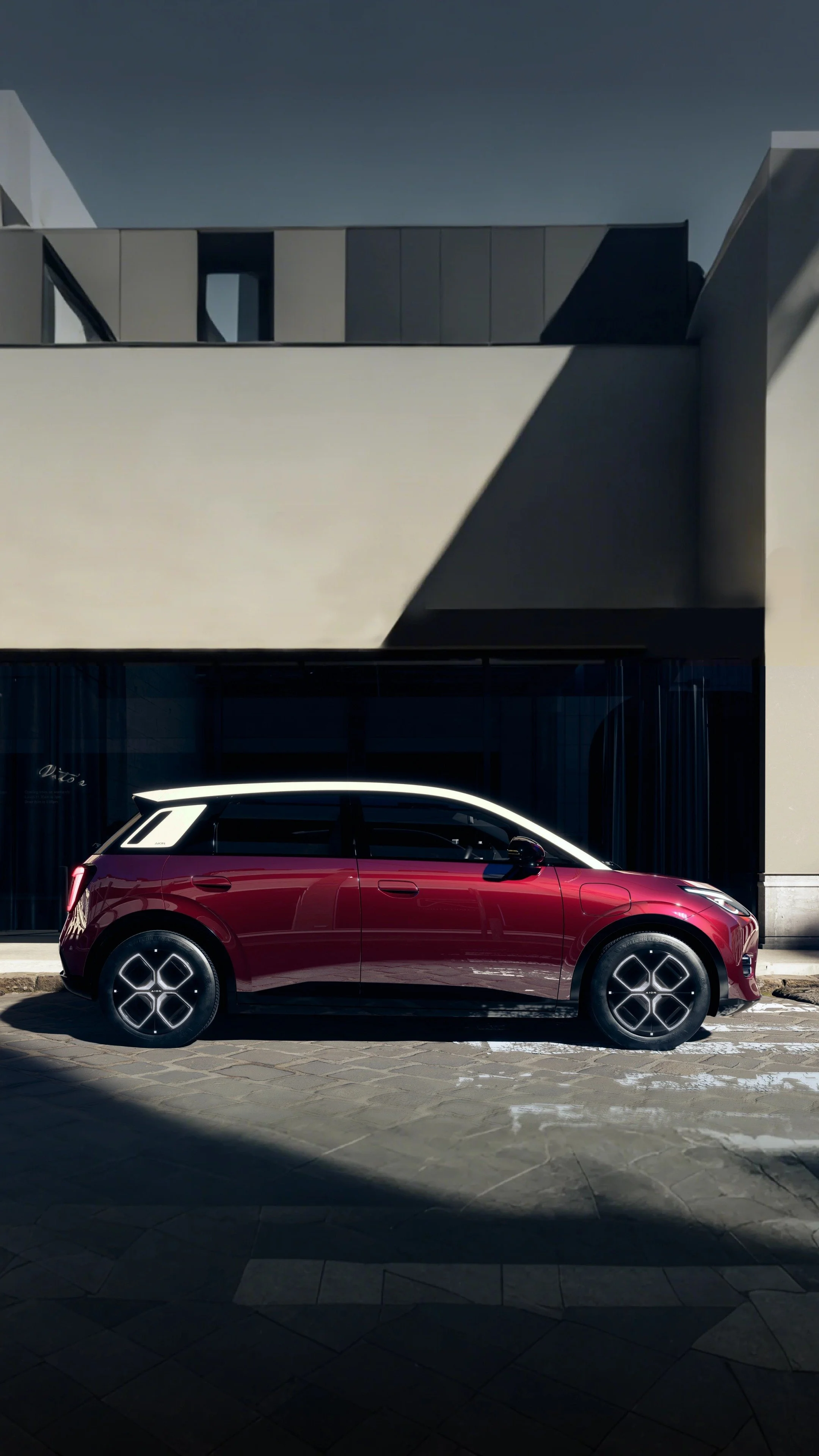 Coche compacto de color rojo con detalles blancos en una calle urbana.