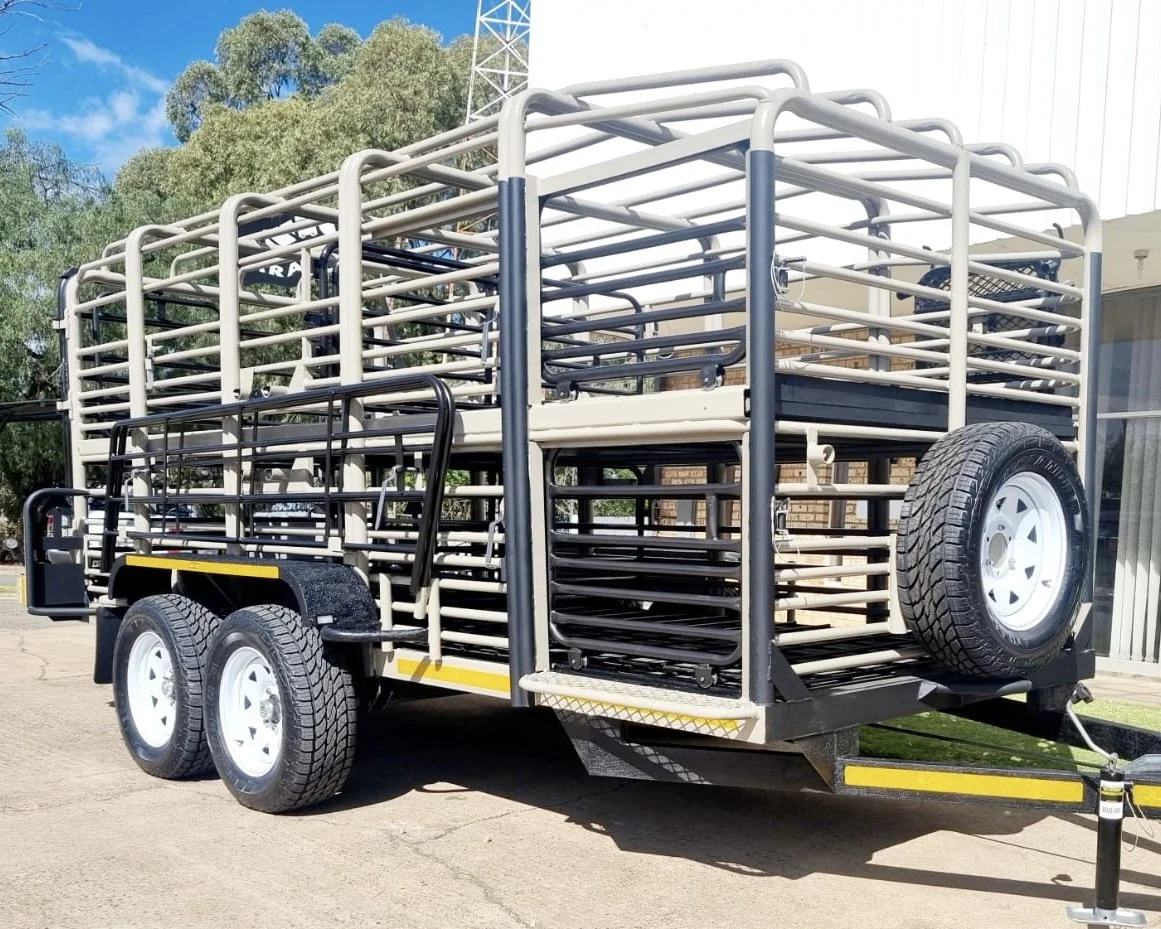 A trailer designed for transporting livestock, with a metal frame and multiple levels, parked outdoors on a concrete surface.