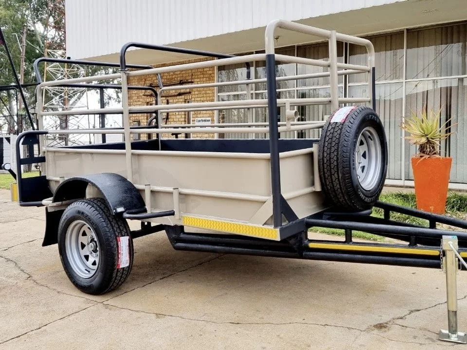 Utility/sheep trailer with side rails and spare tire on display outside a building.