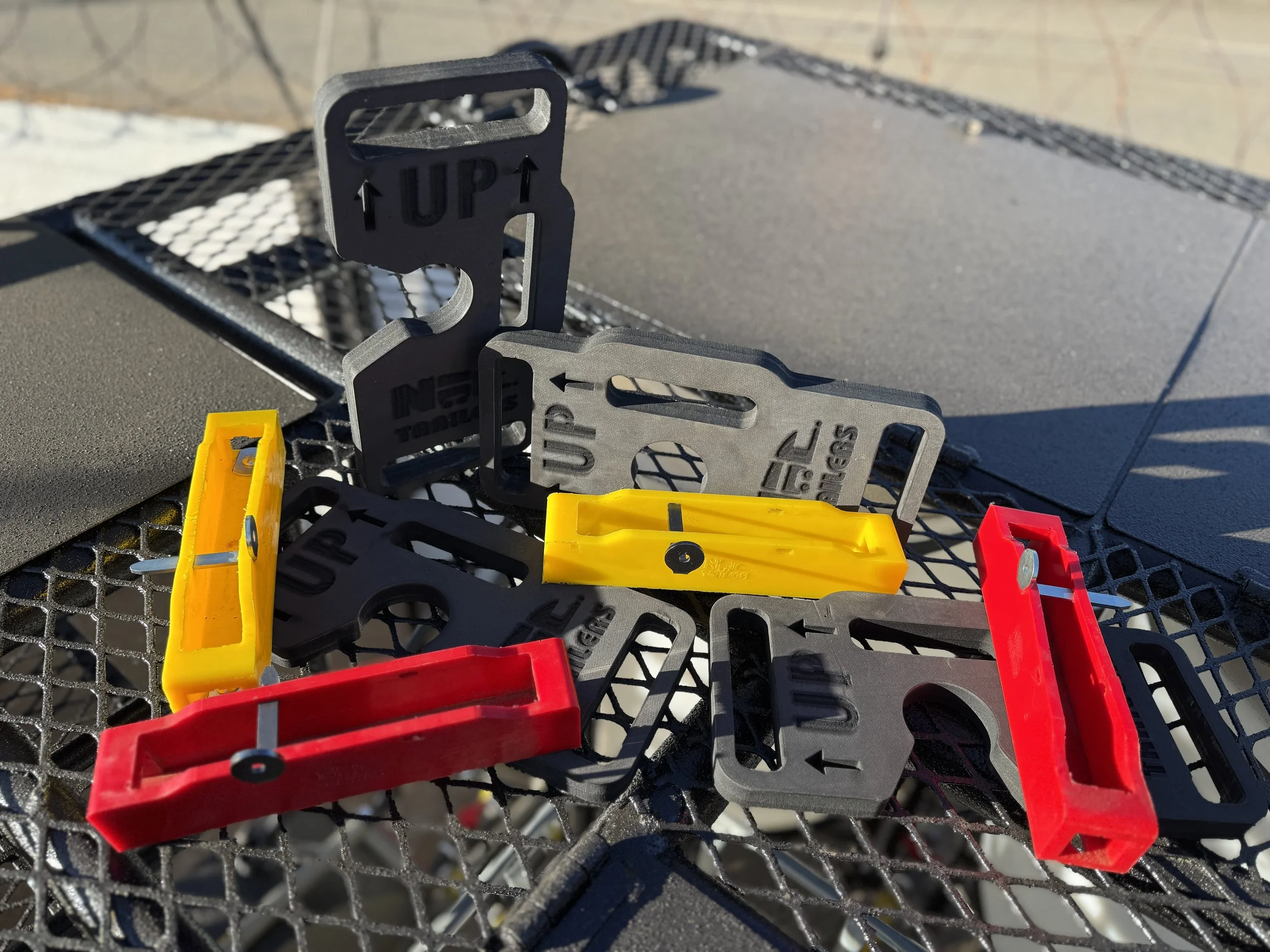 A collection of colorful plastic and metal safety escutcheons with arrows and 'UP' prompts, on a black metal mesh surface.