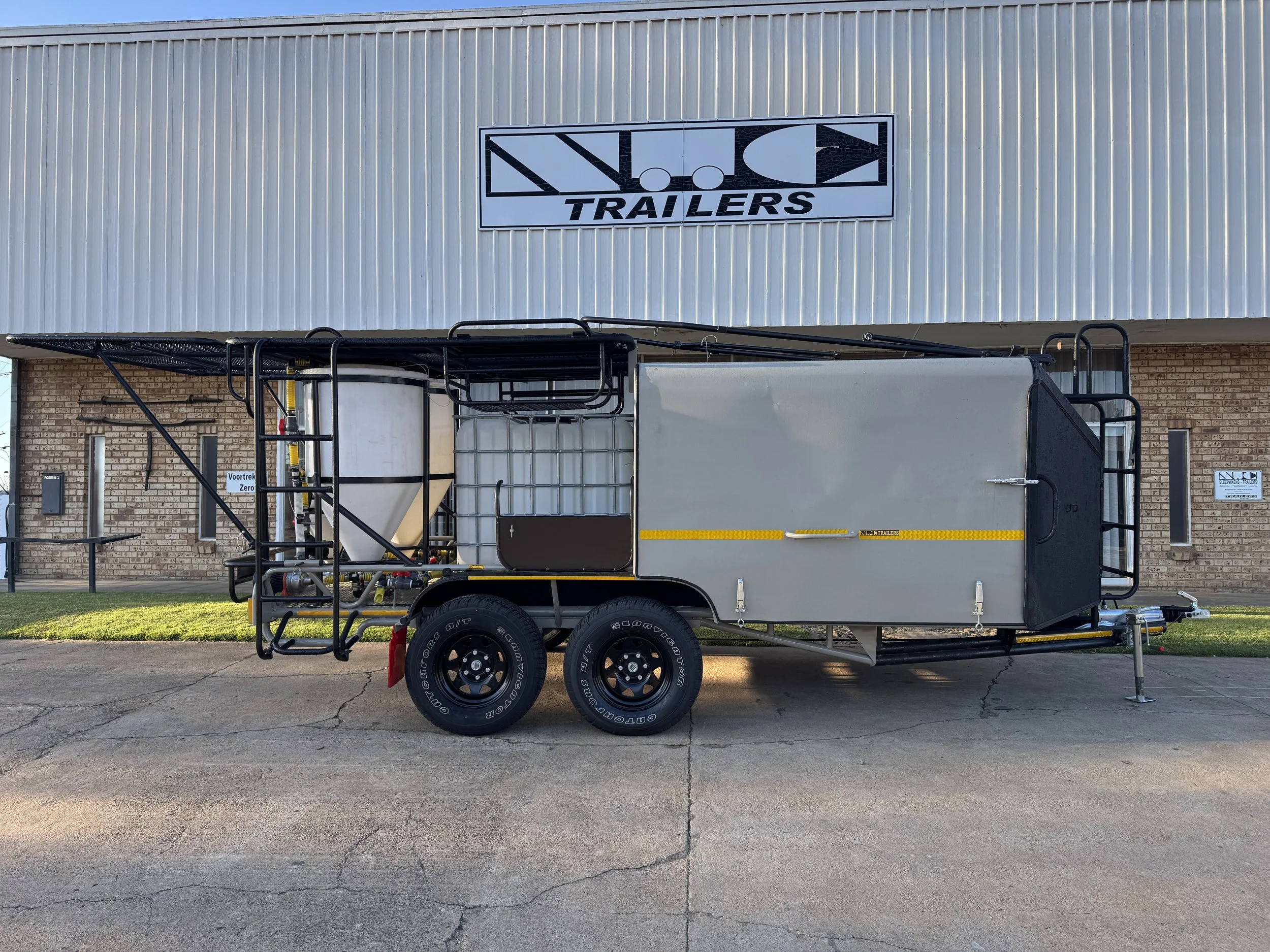 A trailer with equipment and a water tank parked outside a trailer store.
