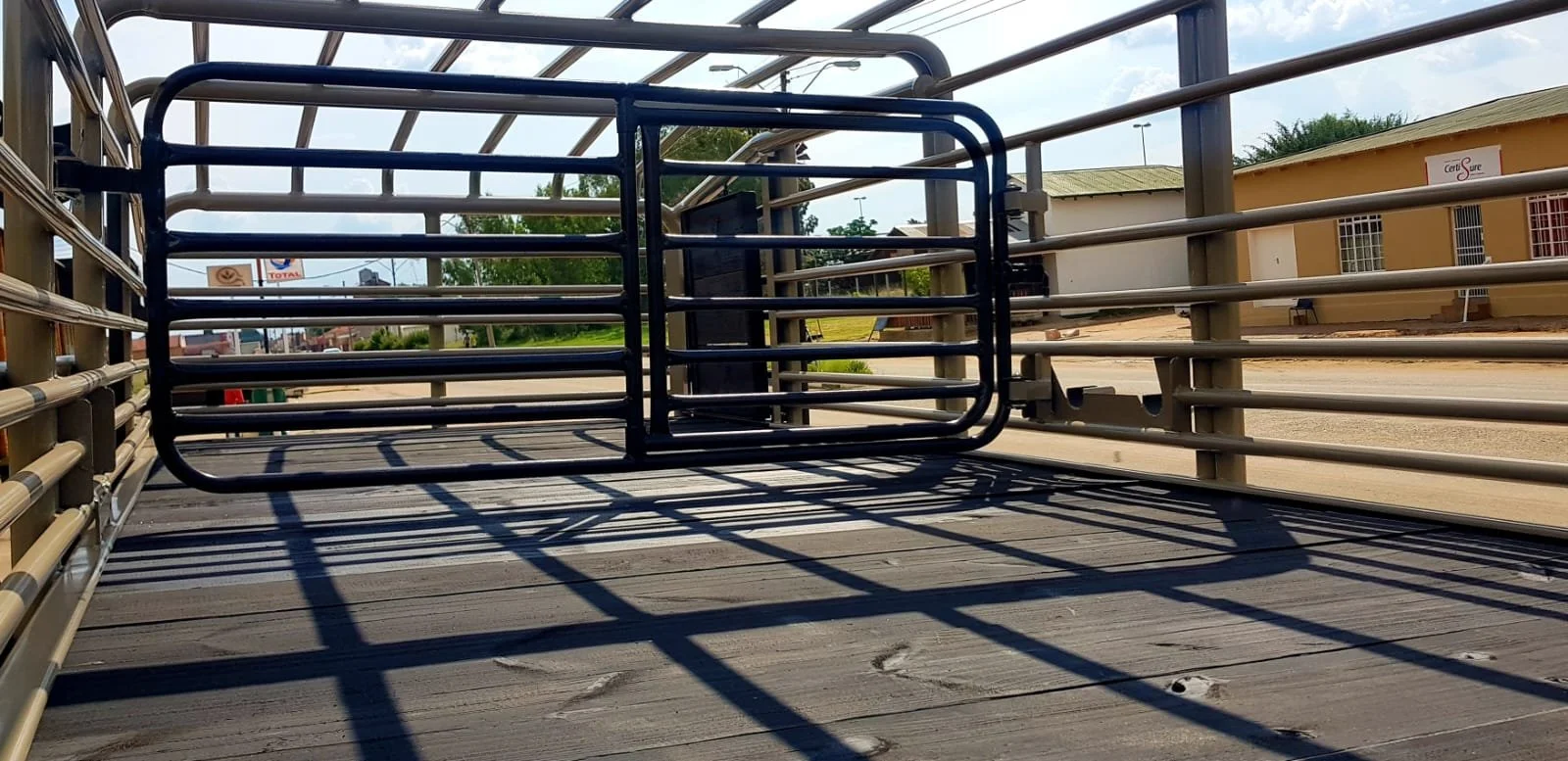 Interior view of an empty livestock trailer with metal bars and a wooden floor, located in an outdoor setting.