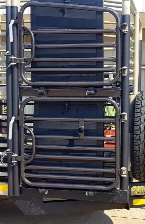 Black folding metal gate attached to a vehicle with a spare tire on the side.