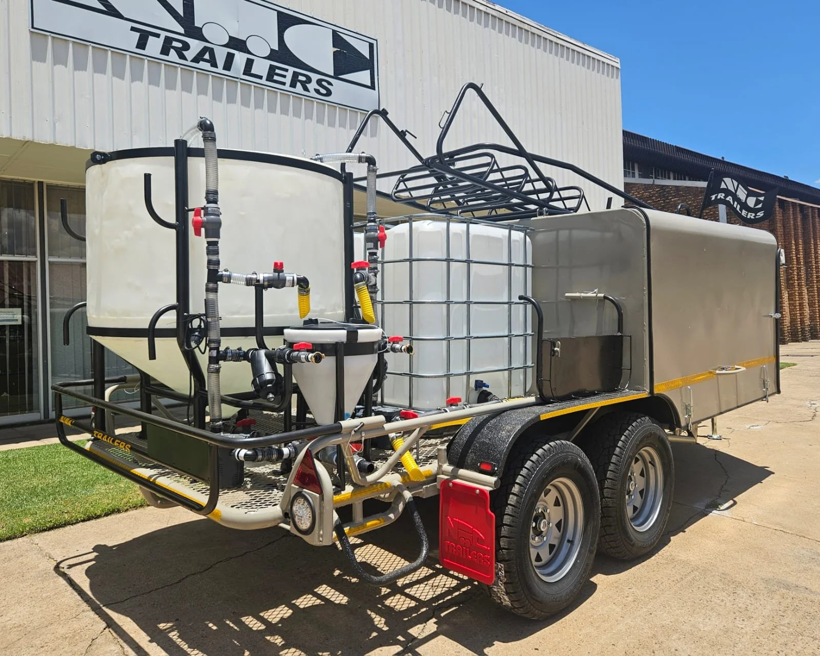 A dual-axle drone trailer equipped with large tanks, hoses, and valves