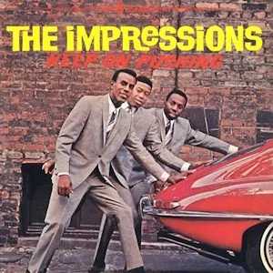 Album cover for 'keep on pushing' by the Impressions. 3 Men in tan suits are pushing a red car.