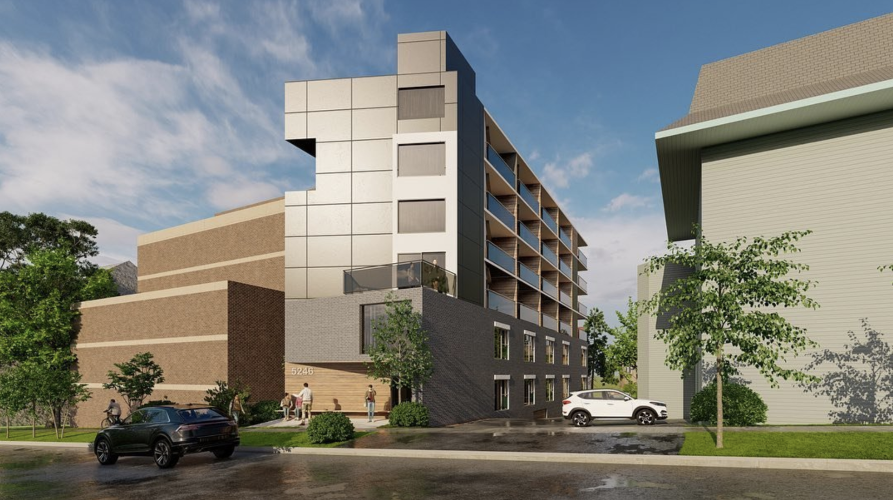 Modern apartment building with a brick base and glass-paneled upper floors, surrounded by trees and parked cars on a sunny day.