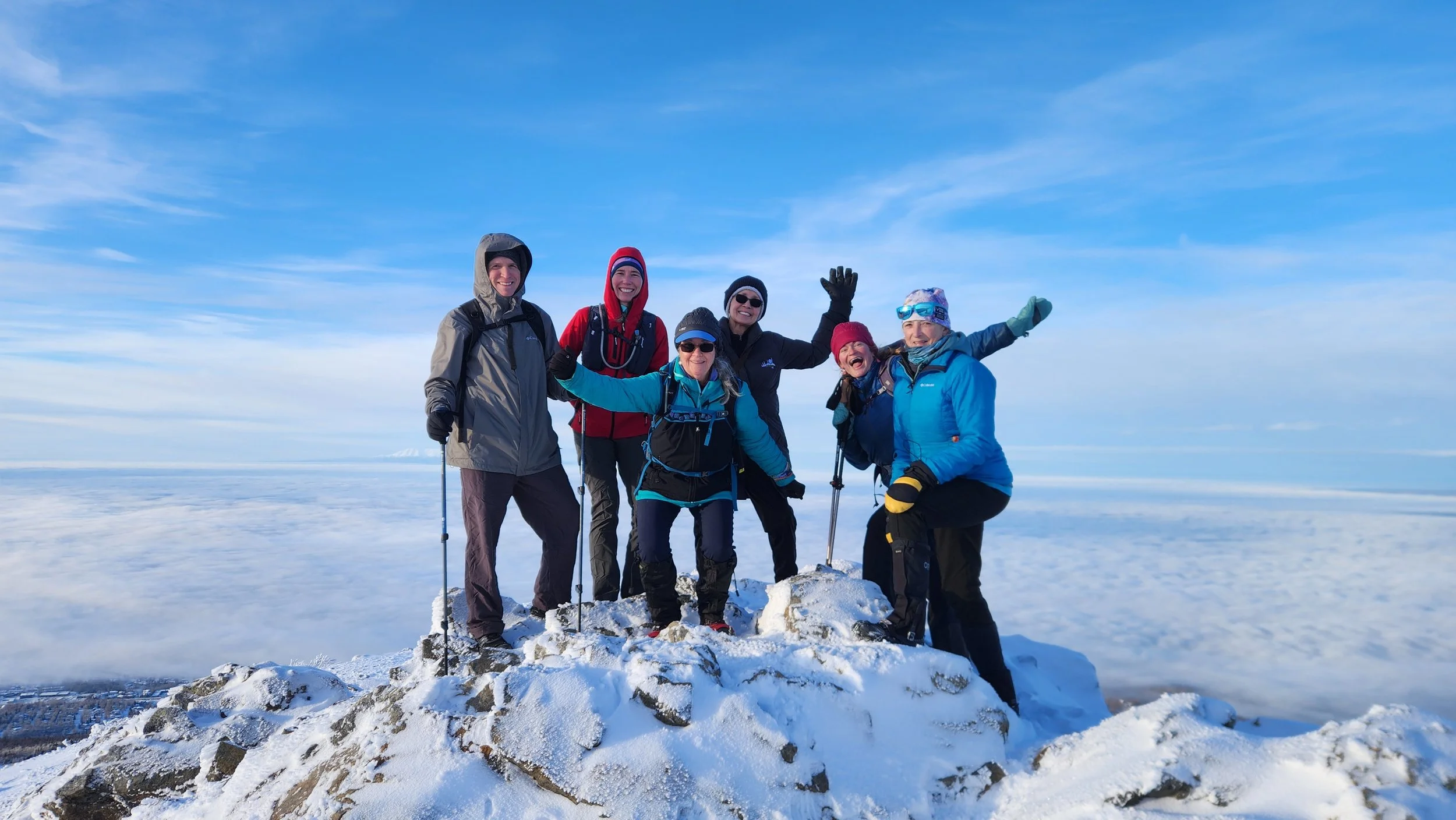 Hikers summit a snowy mountain.