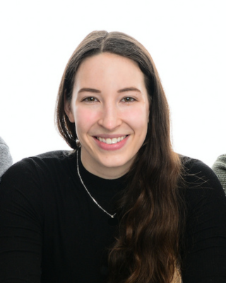 Woman with long brown hair smiling and looking at the camera. 