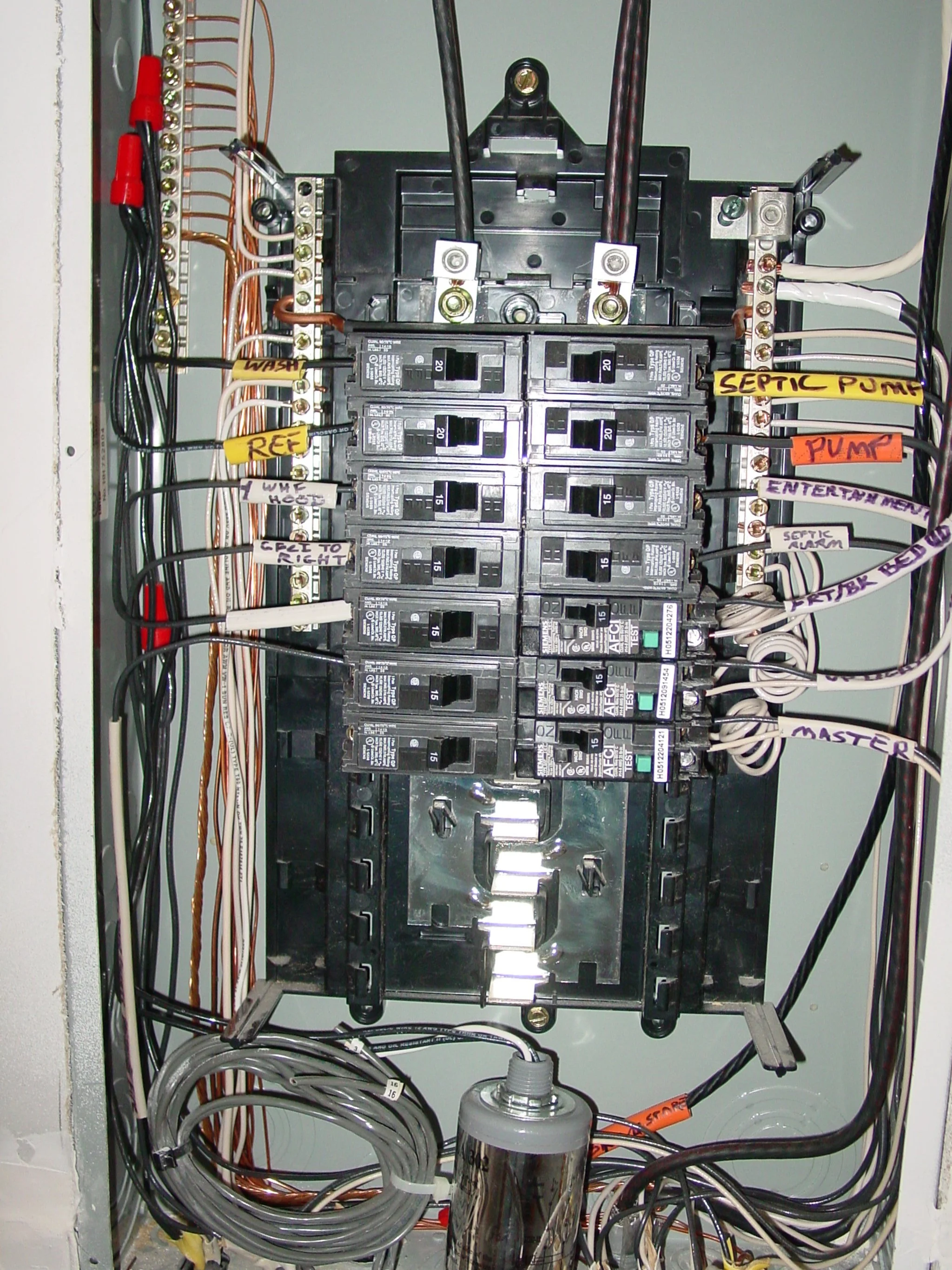 An electrical panel with circuit breakers and wires, labeled with various functions including septic pump, pump, entertainment, septic alarm, master, and others.