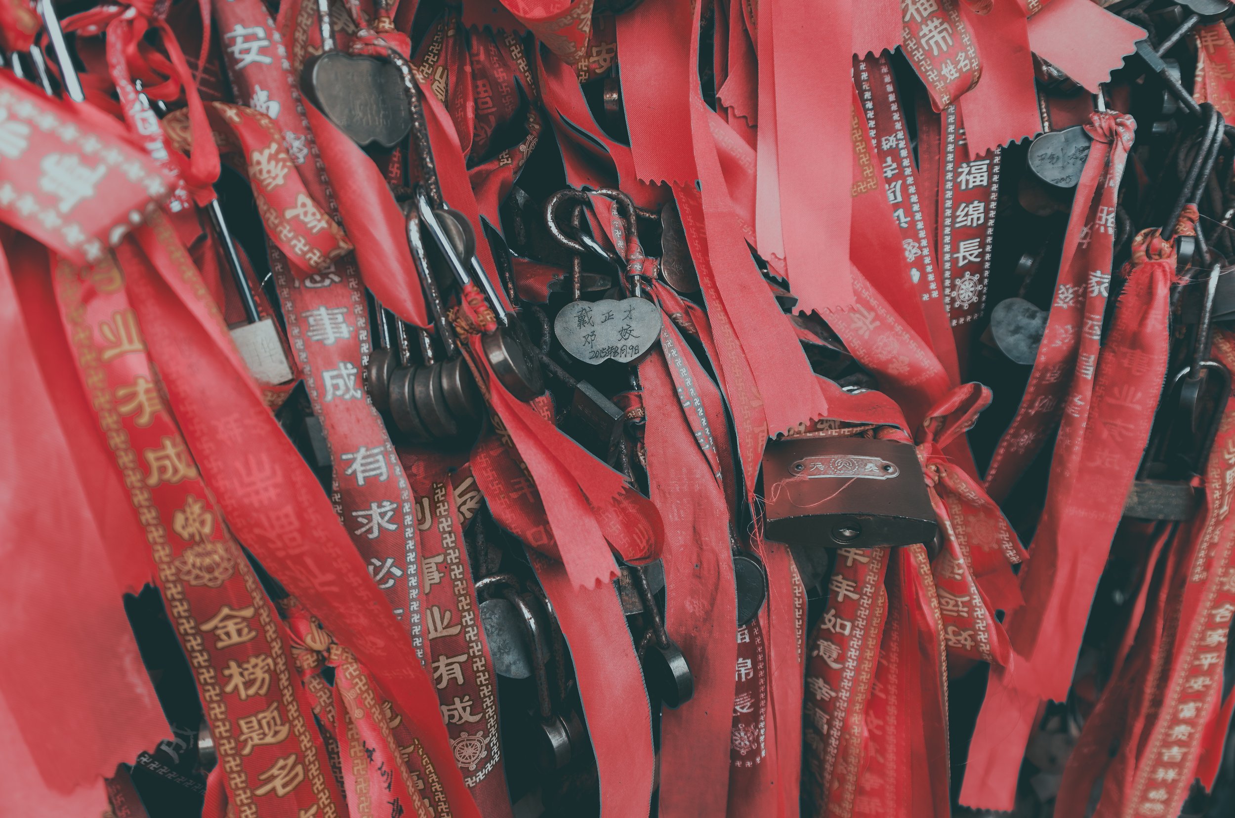 Red ribbons and metal tokens or charms with Chinese characters hanging on a display.