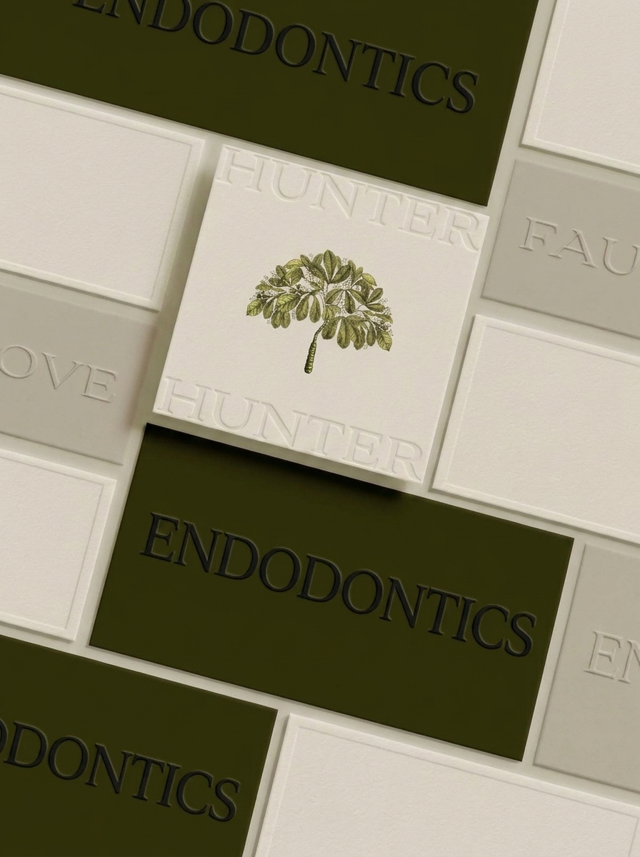 Close-up view of a tile wall with the word 'Endodontics' in black on an olive green tile and the word 'Love' in white on a light gray tile. There is a central white tile with the embossed word 'HUNTER' and an illustration of a green leafy tree.