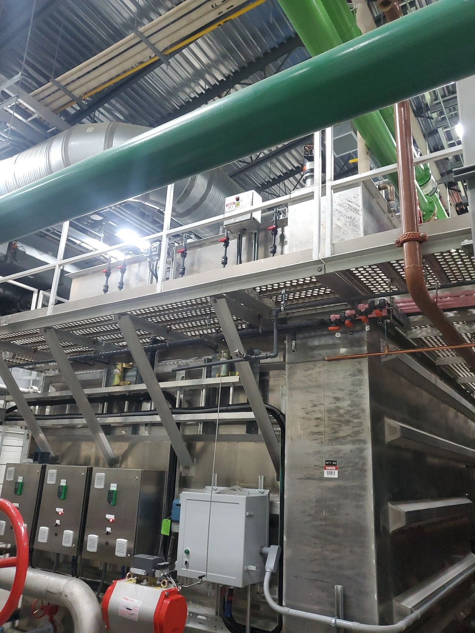 Industrial machinery with pipes, control panels, and metal structures in a factory or power plant.