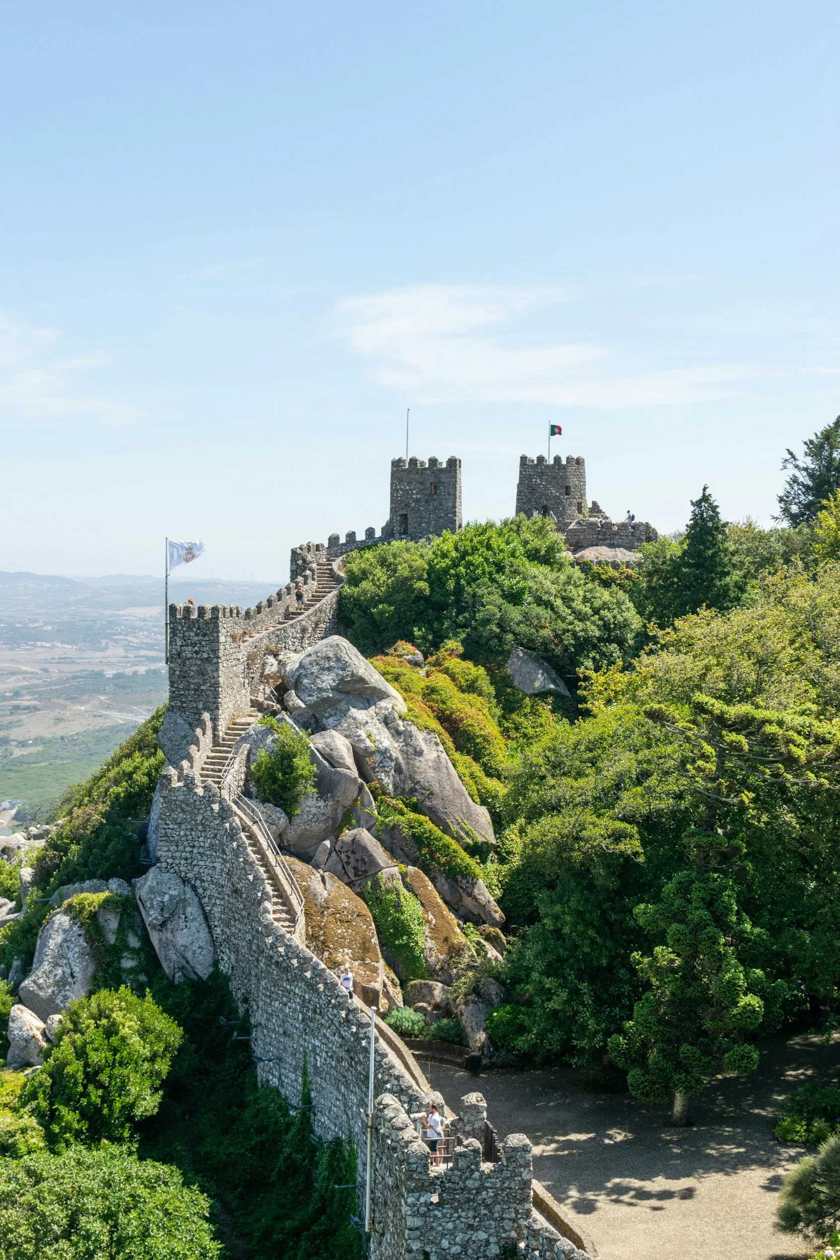 Stone walls of the Moorish Castle in Sintra stretching along a mountain ridge with forested hills in the background