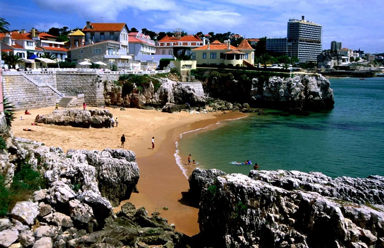 Praia da Rainha Beach in Cascais showing small sandy cove with clear turquoise water surrounded by rocky cliffs