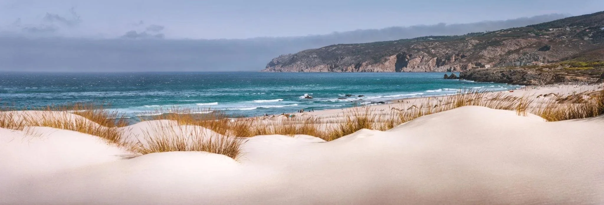 Guincho Beach showing expansive golden sand and powerful Atlantic waves on Cascais coastline