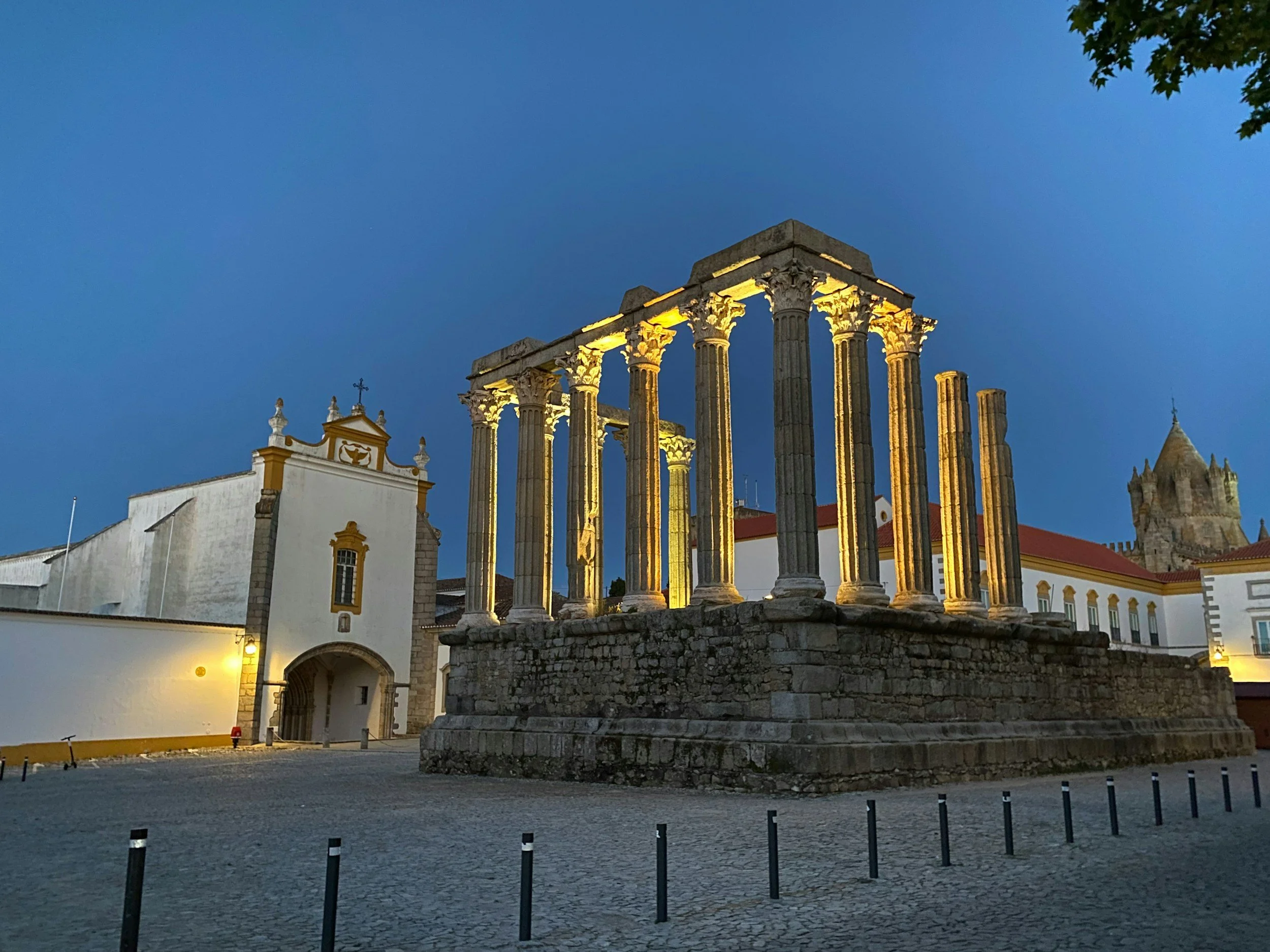 Ancient Roman temple with tall Corinthian columns standing in an open square in Évora, surrounded by historic buildings under a clear sky.