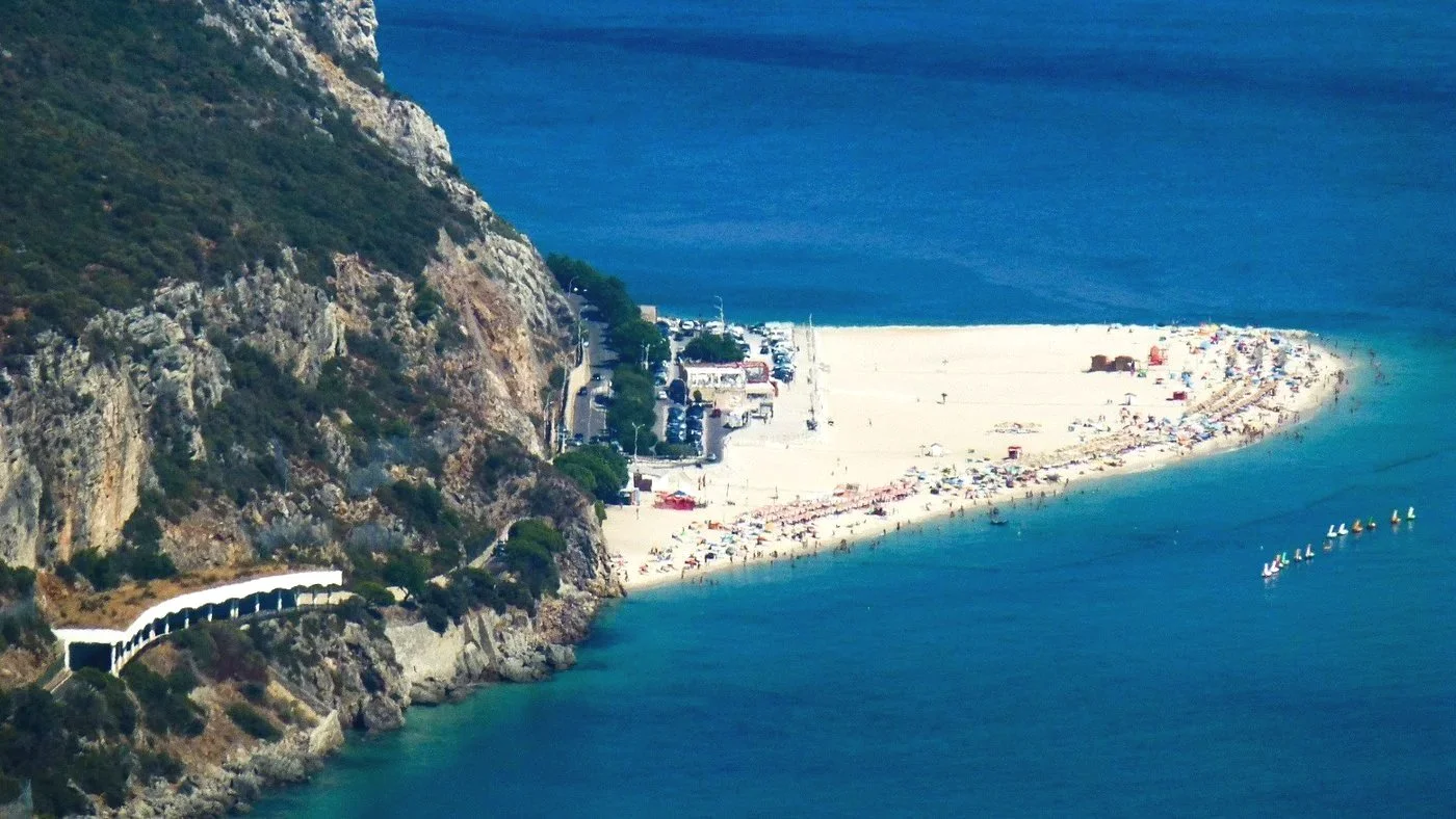 Sandy peninsula extending into clear water at Praia da Figueirinha