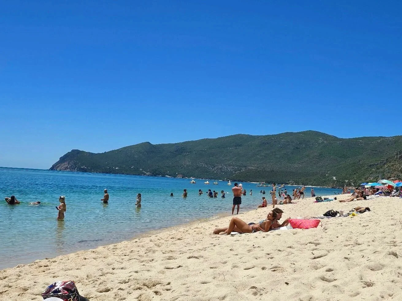 People swimming and relaxing in clear water at Praia da Figueirinha