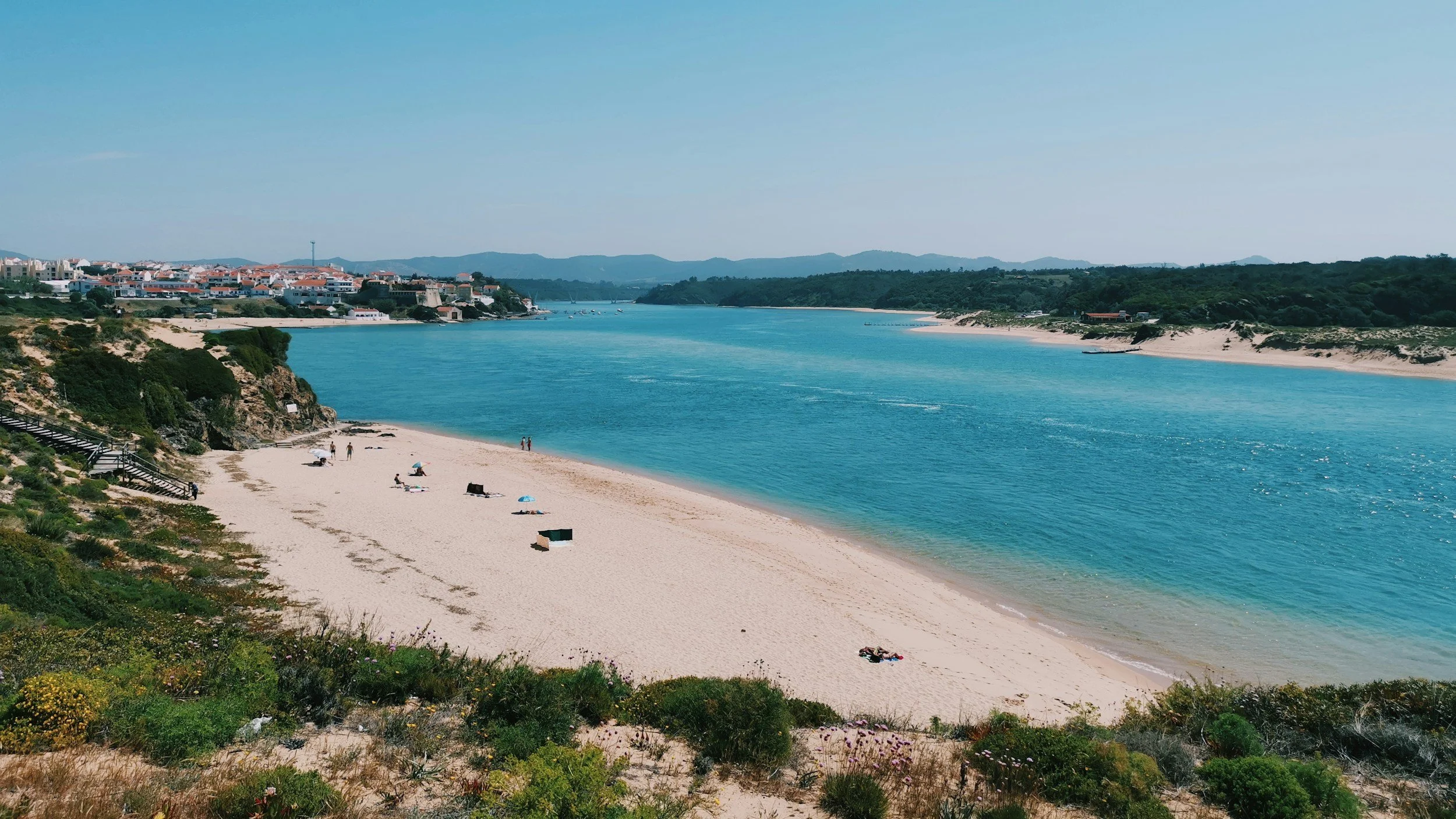 Mira River and sandy shoreline with Vila Nova de Milfontes in the background on Portugal’s Alentejo coast.