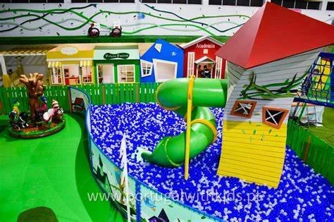 Exciting and colorful indoor play space at Feijão Verde Sintra, offering children the chance to climb a treehouse, slide into a ball pit, enjoy pretend play in a child-sized village, and jump on multiple bounce houses for hours of fun.