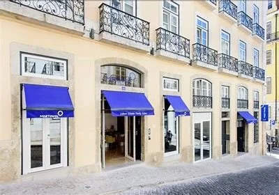 Exterior view of the Martinhal Lisbon Chiado hotel with blue awnings on a narrow street.