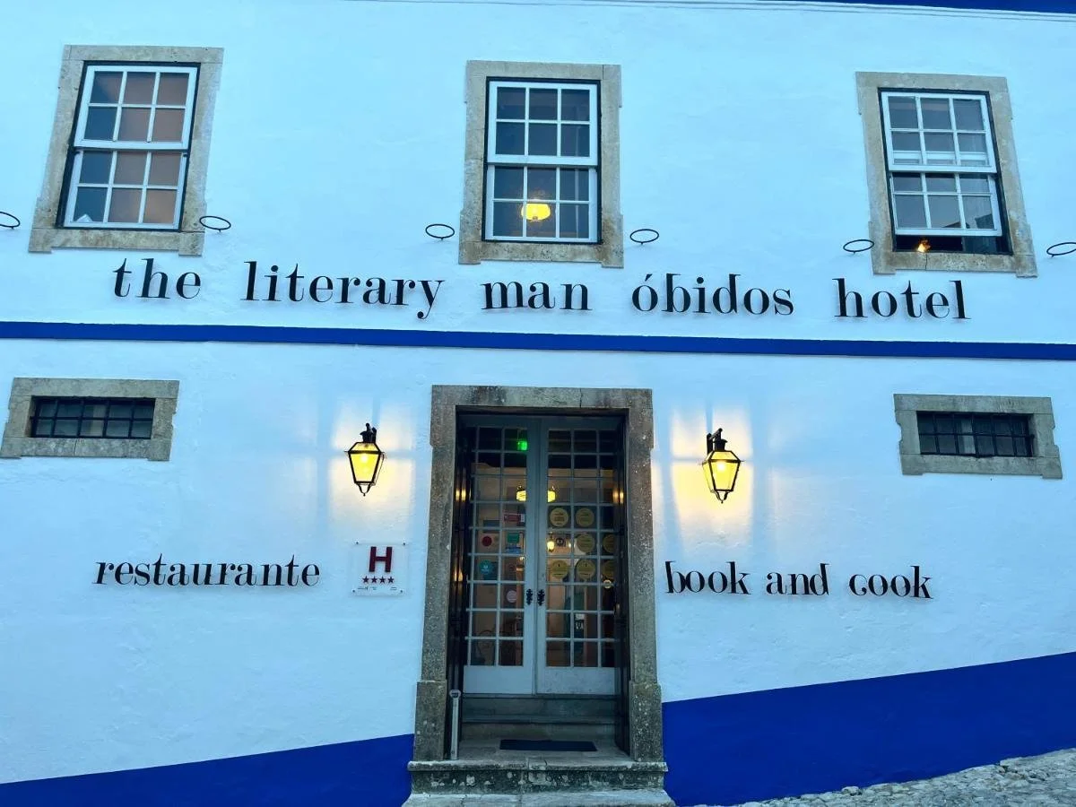 Facade of The Literary Man Óbidos Hotel with restaurant and book-themed exterior in blue and white.