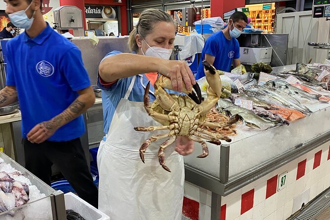 A fishmongr holding up a large crab on the Market Tour and Cooking Class in Lisbon
