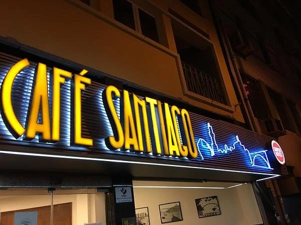 Illuminated sign of Café Santiago Porto with large lettering on the exterior of a building.