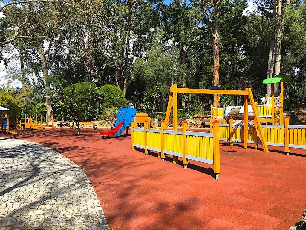 Spacious playground for children ages 3-12 at Parque Marechal Carmona, featuring challenging play structures and a safe rubber-tiled ground.