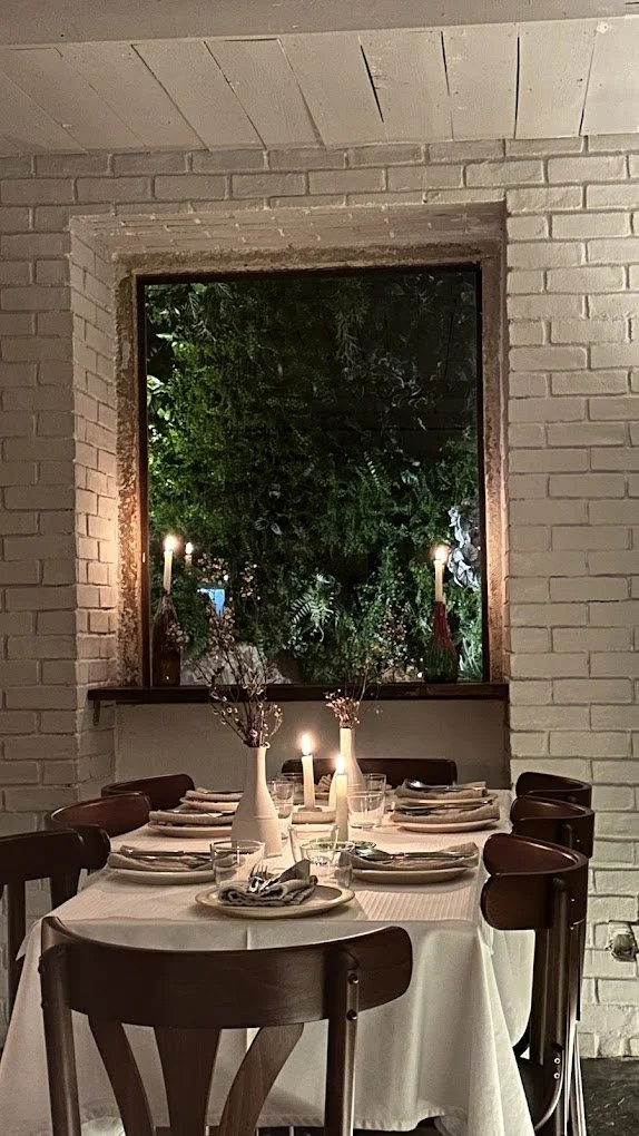 A romantic table setting illuminated by candlelight with a backdrop of greenery at Bar Alimentar an Italian restaurant in Lisbon.