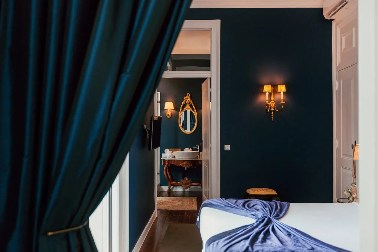 Luxury hotel room at Torrel Palace Lisbon featuring blue velvet bedding with golden accents for an elegant and stylish stay