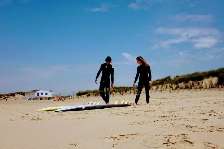 Two surfers walking on the beach after Lisbon Surfing Experience for Beginner and Advanced Surfers