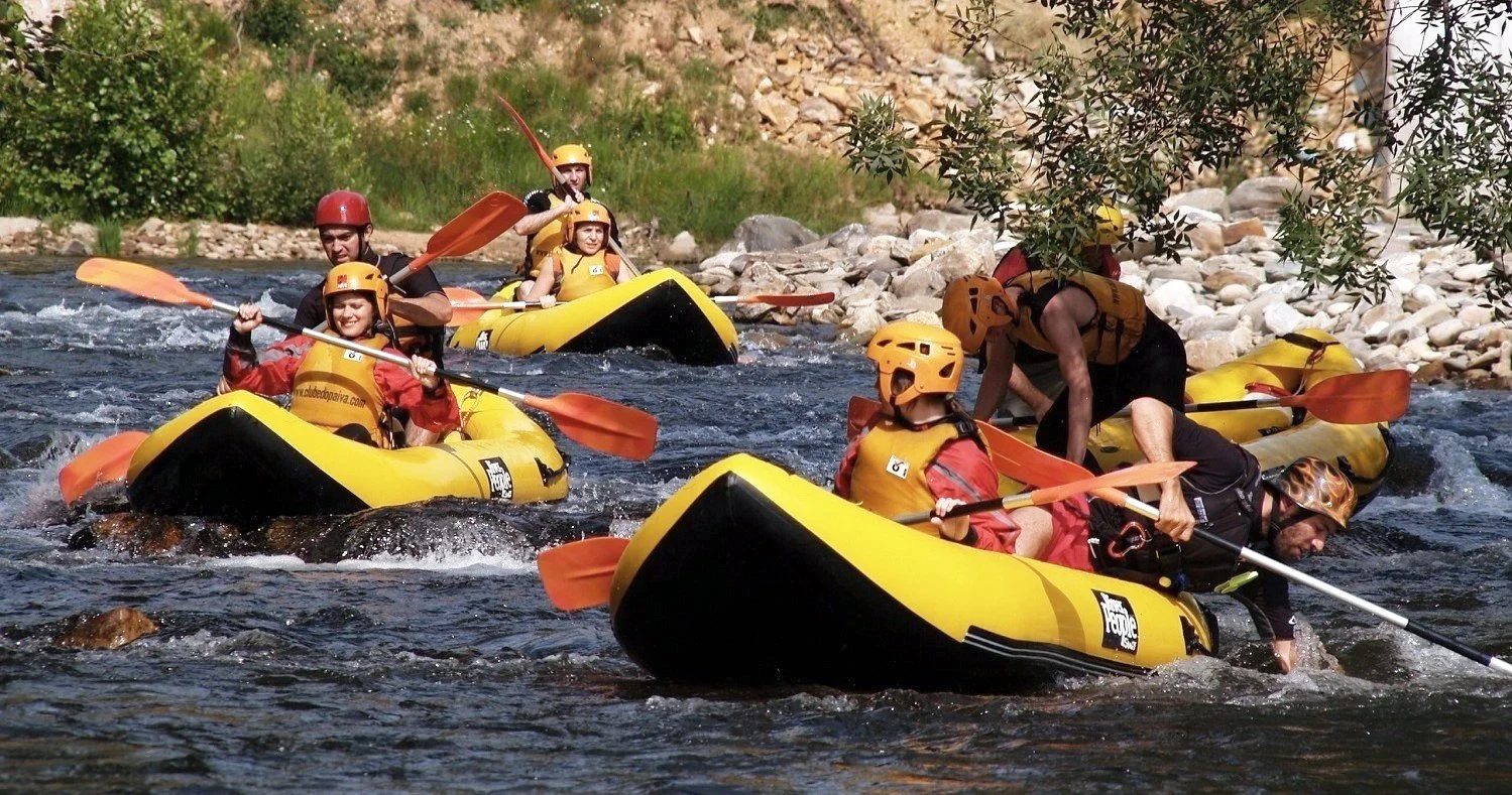 Canoeing adventure on the Paiva River, with people rafting in yellow rafts. Equipped with paddles, helmets, and life jackets, they navigate the river’s clear waters, offering an exciting outdoor experience.